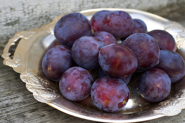 Спелые синие сливы на тарелке