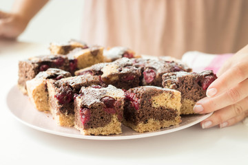 Sliced marble cake filled with cherry holding by a woman.