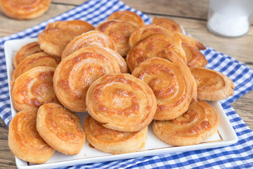 Homemade snail shaped cheese snack on blue checkered table cloth and white plate.