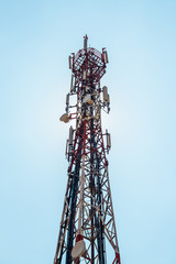 Telecommunication TV antennas with cell phone antennas and satellite dish with blue sky in background