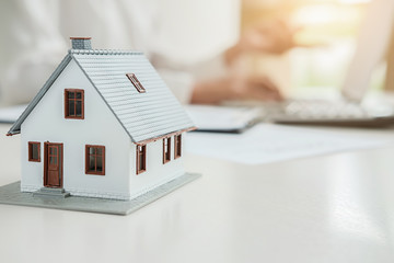 House model with real estate agent and customer discussing for contract to buy house, insurance or...
