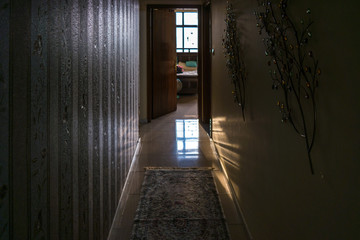 Obraz premium Dark long hallway with view of a room and light coming from the window