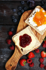 Toast bread with homemade strawberry jam and apricot marmalade on rustic table served with butter for breakfast or brunch