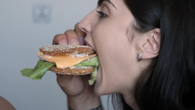 Young couple fun eat together bite a tasty sandwich simultaneously