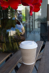 vase with tulips and a paper cup with coffee street restaurant