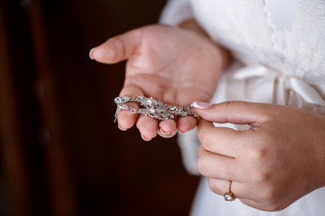 the bride's hands hold the silver earrings. Elegant manicure. Expensive decorations