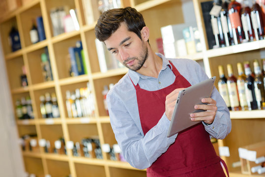 Man in liquor store holding tablet computer