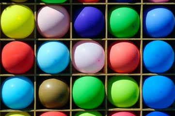 Many bright colorful balloons in wooden boxes.