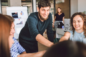 Fototapeta premium Entrepreneurs folded their hands together sitting at a table in the office