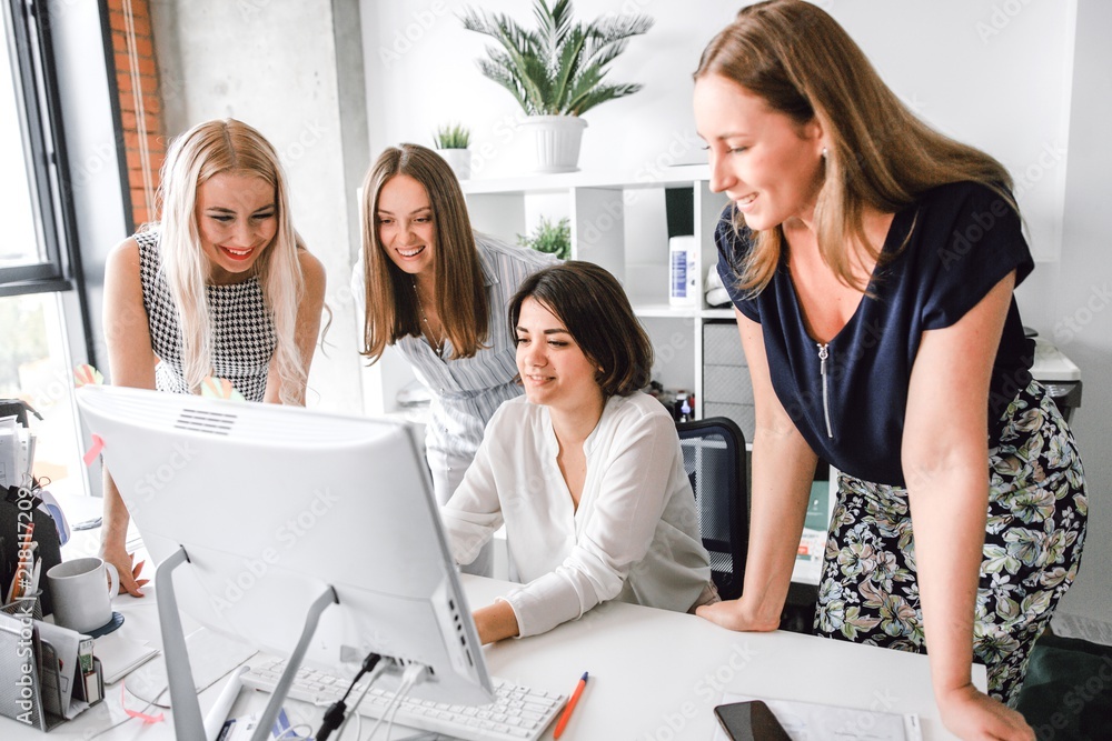 Wall mural women's team standing at the same table working at the computer