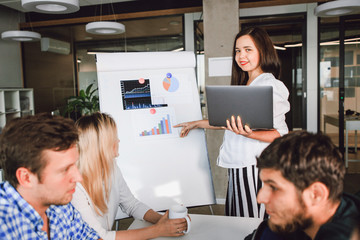 Obraz premium Girl entrepreneur shows colleagues sales schedule standing at the easel in the office