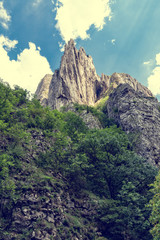 Fototapeta premium High mountain peak and forest against blue sky with clouds in Turda gorge, Romania