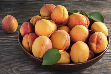 Naklejka na ściany i meble Fresh ripe apricots in a ceramic bowl on a wooden table.