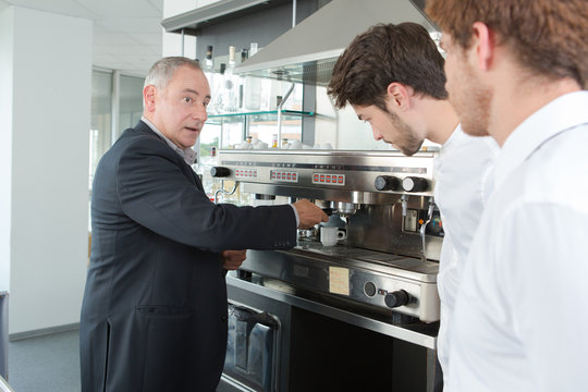 Young waiters learning how to use coffee machine