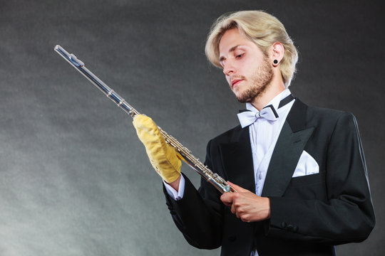 Elegantly dressed musician man cleaning flute