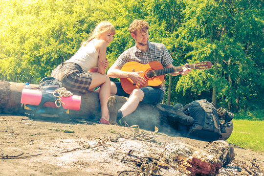 Young couple camping playing guitar outdoor