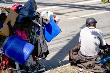 Poor old man or beggar begging you for help sitting at dirty slum with his stuff at sideroad....