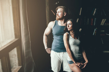 Muscular man and a pretty woman looking in the window