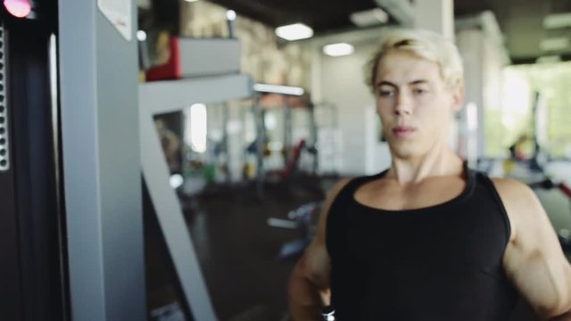 Close up of fitness young man using rowing machine in the gym