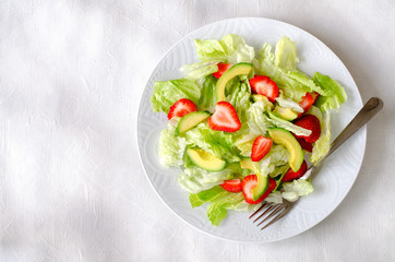 Salad with avocado, strawberries and lettuce on white background