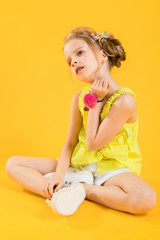 Obraz na płótnie Canvas A teenage girl is sitting on a yellow background.