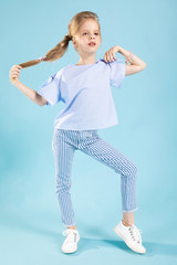 Full-length portrait of a beautiful girl in blue clothes on a blue background.
