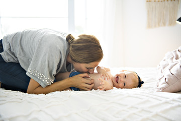 Mother and baby girl on a white bed