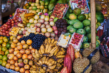 Asian exotic fruits. Market stall with variety of organic fruits. Colorful fruits in the marketplace. Bright summer background. Healthy, organic food. Natural nutrition for diet. Selective focus.