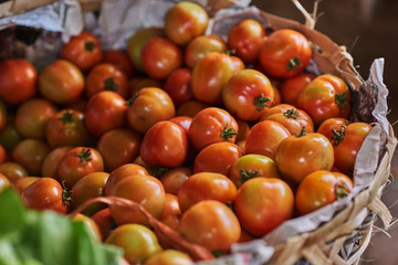 Big handmade basket with big orange ripe tomatoes. Rustic market with tomatoes on sale, sweet and juicy berries.