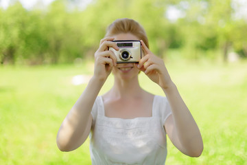 Portrait of beautiful young smiling woman with camera at summer green park