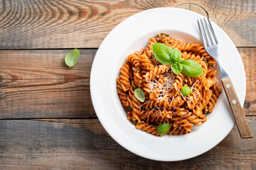 Fusilli pasta with tomato sauce, garlic, Basil and Parmesan cheese on an old wooden table. Top view with copy space. Flat lay