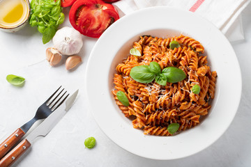 Fusilli pasta with tomato sauce, garlic, Basil and Parmesan cheese on white background. Top view. Flat lay