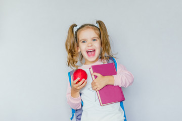 back to school. funny little girl from elementary school with a book,a bag and an apple. education. child with a book.	