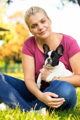 Smiling young woman playing with puppy. Her best friend