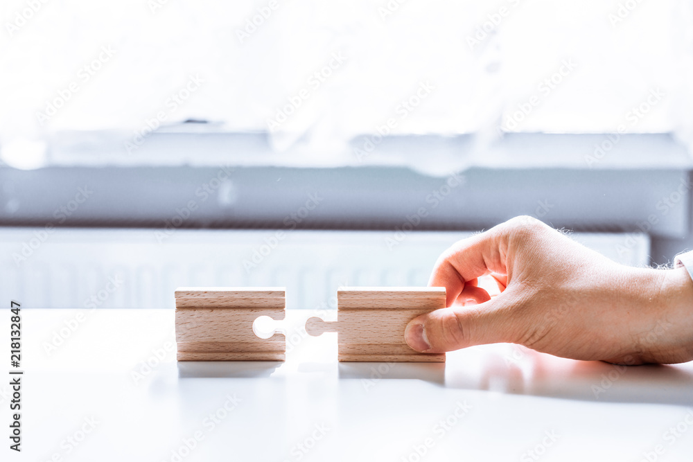 Poster hand holding a wooden jigsaw puzzle with blank space. there is a matching puzzle next to it. the con