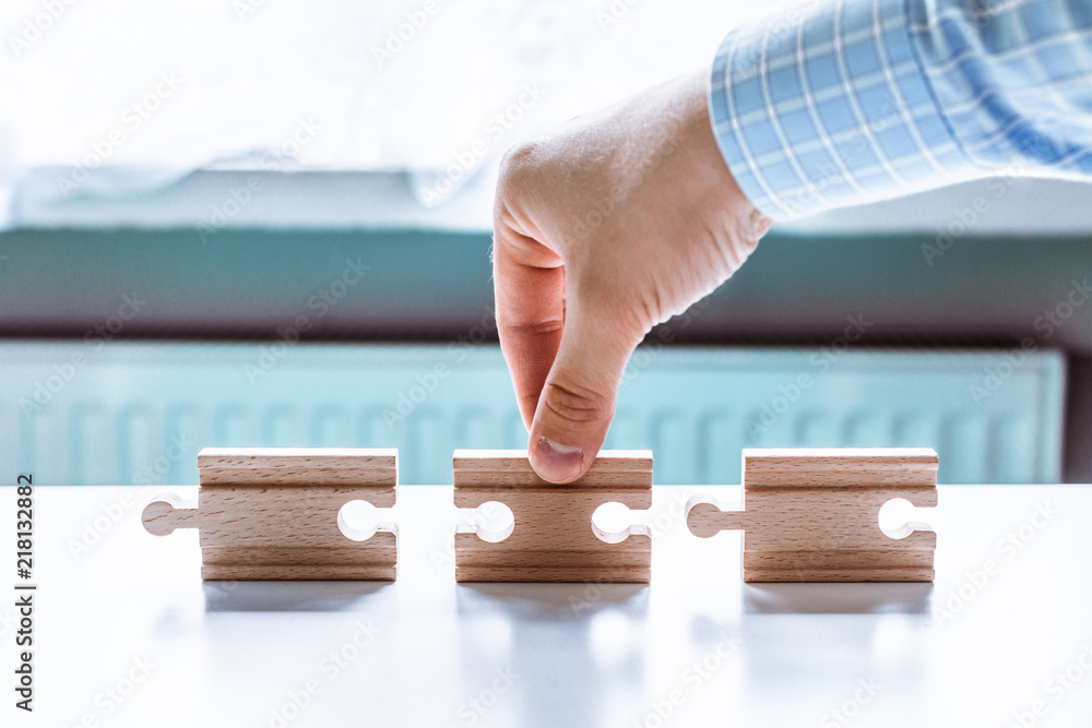 Poster hand holding a wooden jigsaw puzzle with blank space. there is a matching puzzle next to it. the con