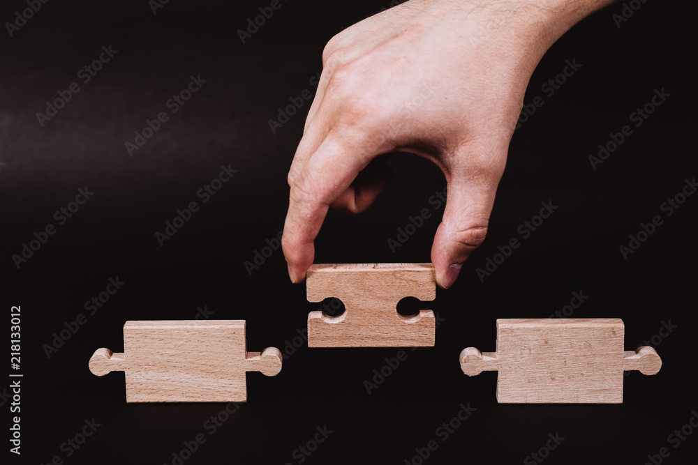 Poster hand holding a wooden jigsaw puzzle with blank space. there is a matching puzzle next to it. the con