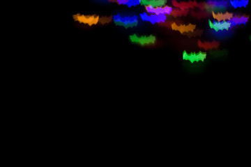 holidays, decoration and party concept - defocused bokeh multicolor lights in shape of bats for halloween background. copy space