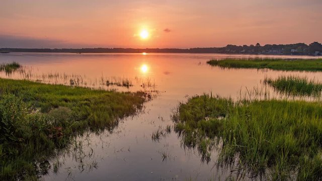 Summer sunrise over a New England cove with sculling practice and other boats in the river. 4K, 24 FPS, 4096 X 2304