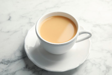 Cup with black tea and milk on marble table