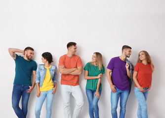 Group of young people in jeans and colorful t-shirts on light background