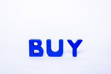 Inscription BUY with colorful letters isolated. BUY inscription created from wooden letters in various colors. Business and shopping concept.