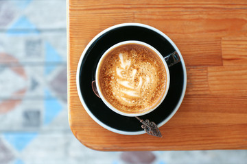 Cup of fresh aromatic coffee on wooden table, top view