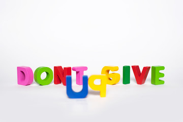 Word DONT GIVE UP. Wooden letters isolated on a white background with the word DONT GIVE UP. The concept of courage and stubbornness in the pursuit of the goal.