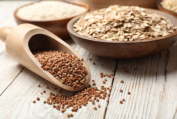 Scoop with buckwheat on wooden table, closeup. Grains and cereals