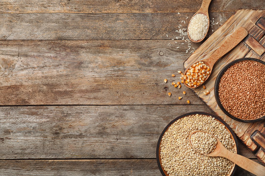 Flat lay composition with different types of grains and cereals on wooden background