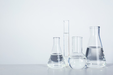 Laboratory glassware with liquid on table against light background. Chemical analysis