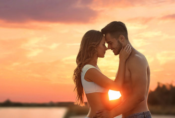 Naklejka premium Happy young couple in beachwear outdoors at sunset