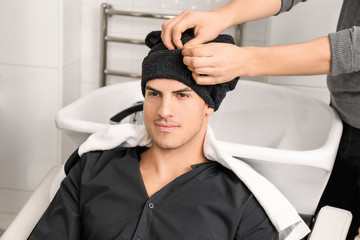 Hairdresser drying client's hair with towel in beauty salon