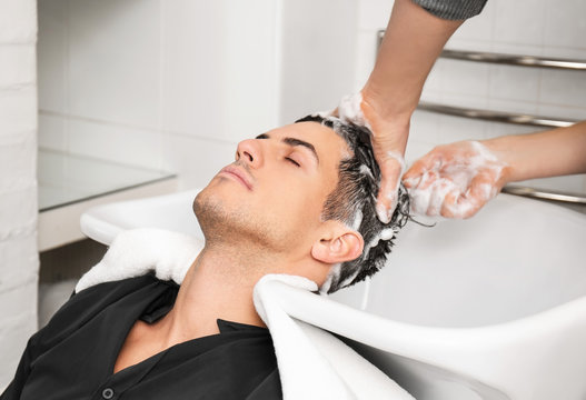 Hairdresser washing client's hair in beauty salon